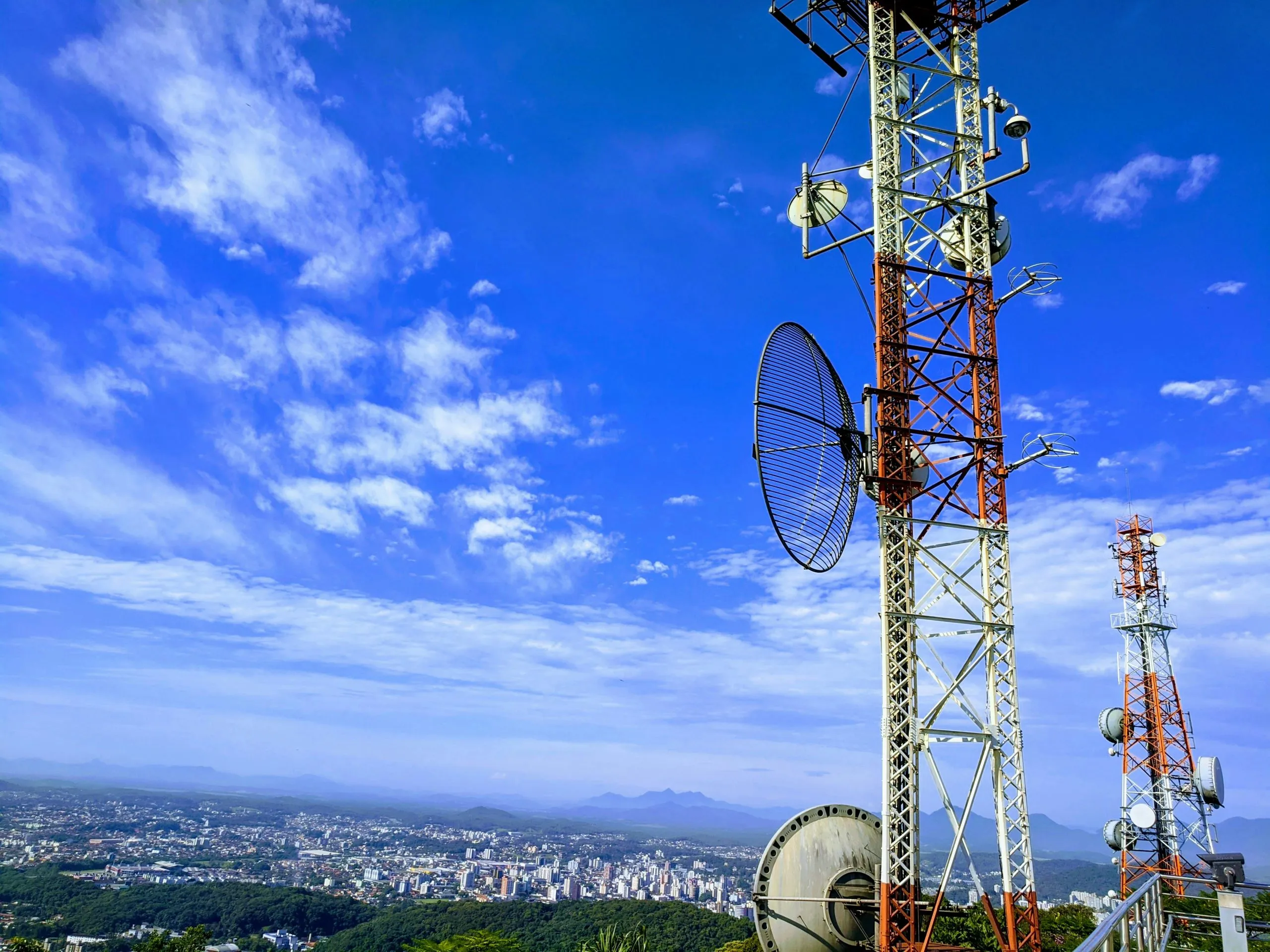 thiago-santos-T_vGku2dUYQ-unsplash-scaled Photo of telecommunications masts overlooking a city.